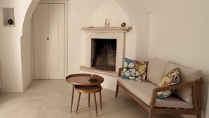 Ein schlichter Wohnraum mit einer Couch, einem runden Holztisch und einem Kamin.