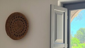 Ein Zimmer mit Fenster, einer gewebten Wandbehängung und Blick auf Grün.