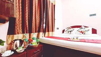 Quarto de hotel com uma cama, cómoda de madeira, espelho e janela com cortinas.