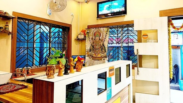 Un espace d’accueil comprenant un téléviseur, un ventilateur, une statue et une fenêtre ornée d’un motif géométrique.