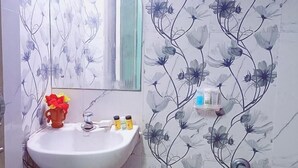 Une salle de bain avec un lavabo blanc, un miroir et des carreaux à motifs floraux.