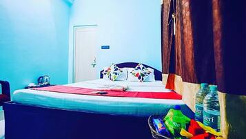 A bedroom with a bed, a trash bin, and a water bottle.