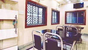 Une chambre d’hôtel comprenant un coin repas, un lit, une télévision et une fenêtre ornée d’une grille décorative.
