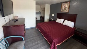 Habitación de hotel con cama, escritorio, silla, televisión y un cuadro en la pared.
