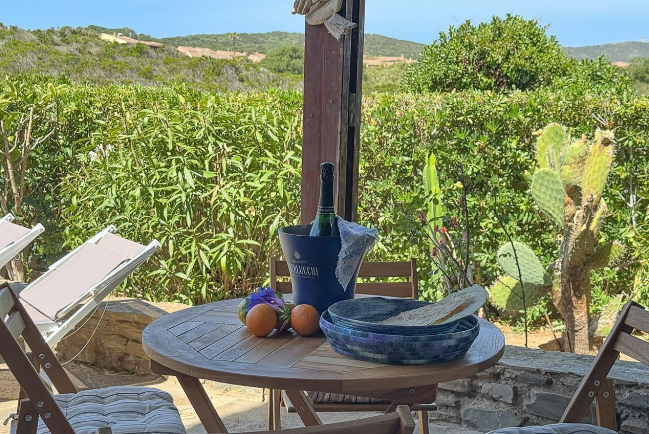A round wooden table with a bottle, oranges, and a woven basket.