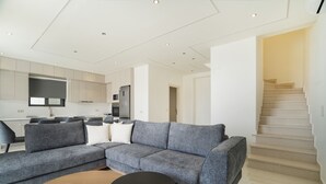 Ein stilvoller Wohnbereich mit einem grauen Ecksofa, einem Holztisch und einer Küche im Hintergrund.