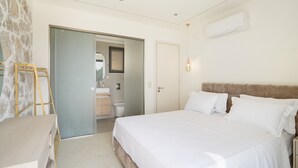 Ein Schlafzimmer mit einem großen Bett, einem Kleiderschrank, einem Badezimmer und einer Steinwand.