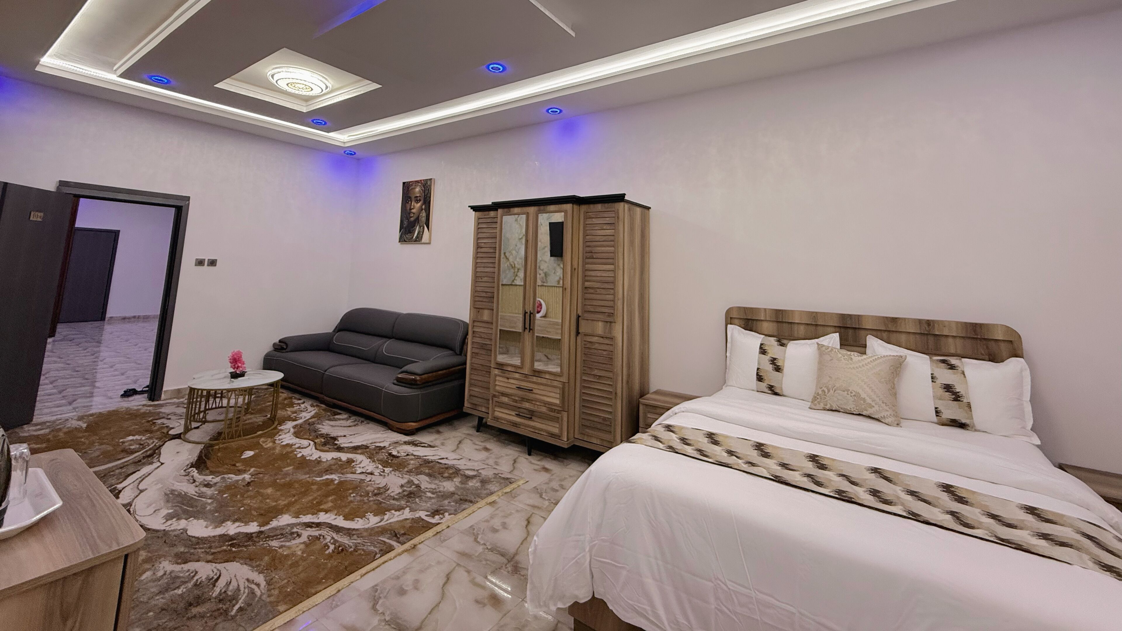 Een slaapkamer met een bed, een bank, een kledingkast en een bijzettafeltje met een vaas.