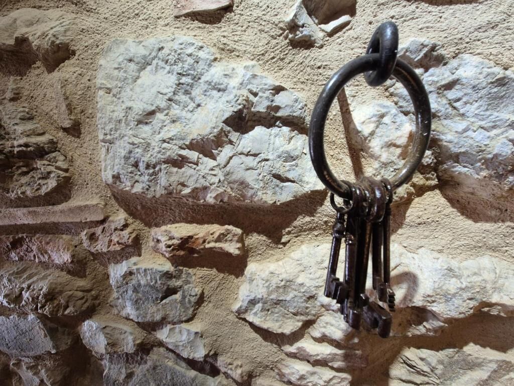 Um muro de pedra com um argola de metal e chaves.