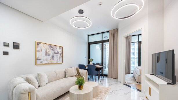 Una sala de estar moderna con sofá, mesa de centro, televisor y comedor.
