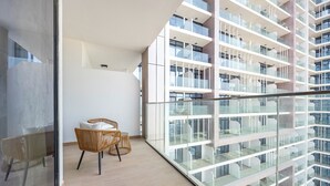 Un apartamento moderno con balcón, muebles de mimbre y vistas a un edificio alto.