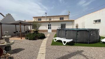 Un espacio cubierto con mobiliario exterior, un jacuzzi y un pequeño jardín.