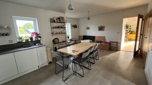 Een moderne keuken met een eetgedeelte, witte kasten en uitzicht door een raam.