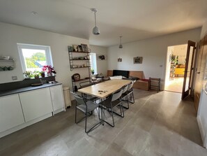 Eine moderne Küche mit Essbereich, weißen Schränken und Blick durch ein Fenster.
