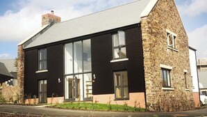 Een modern huis met twee verdiepingen, een gevel van natuursteen, grote ramen en een schuin dak.