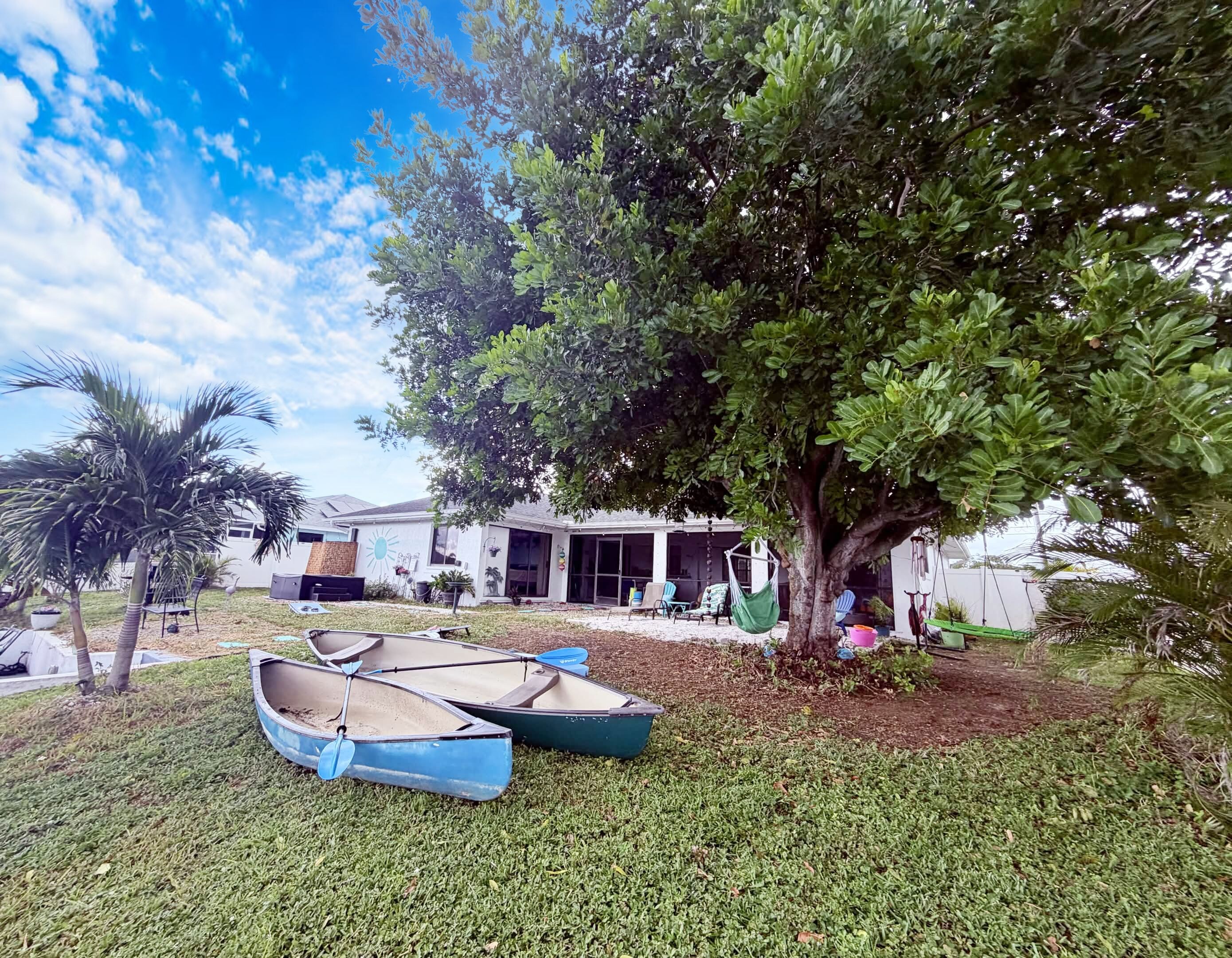 A residential property with a lawn, two boats, and a house with a patio area.