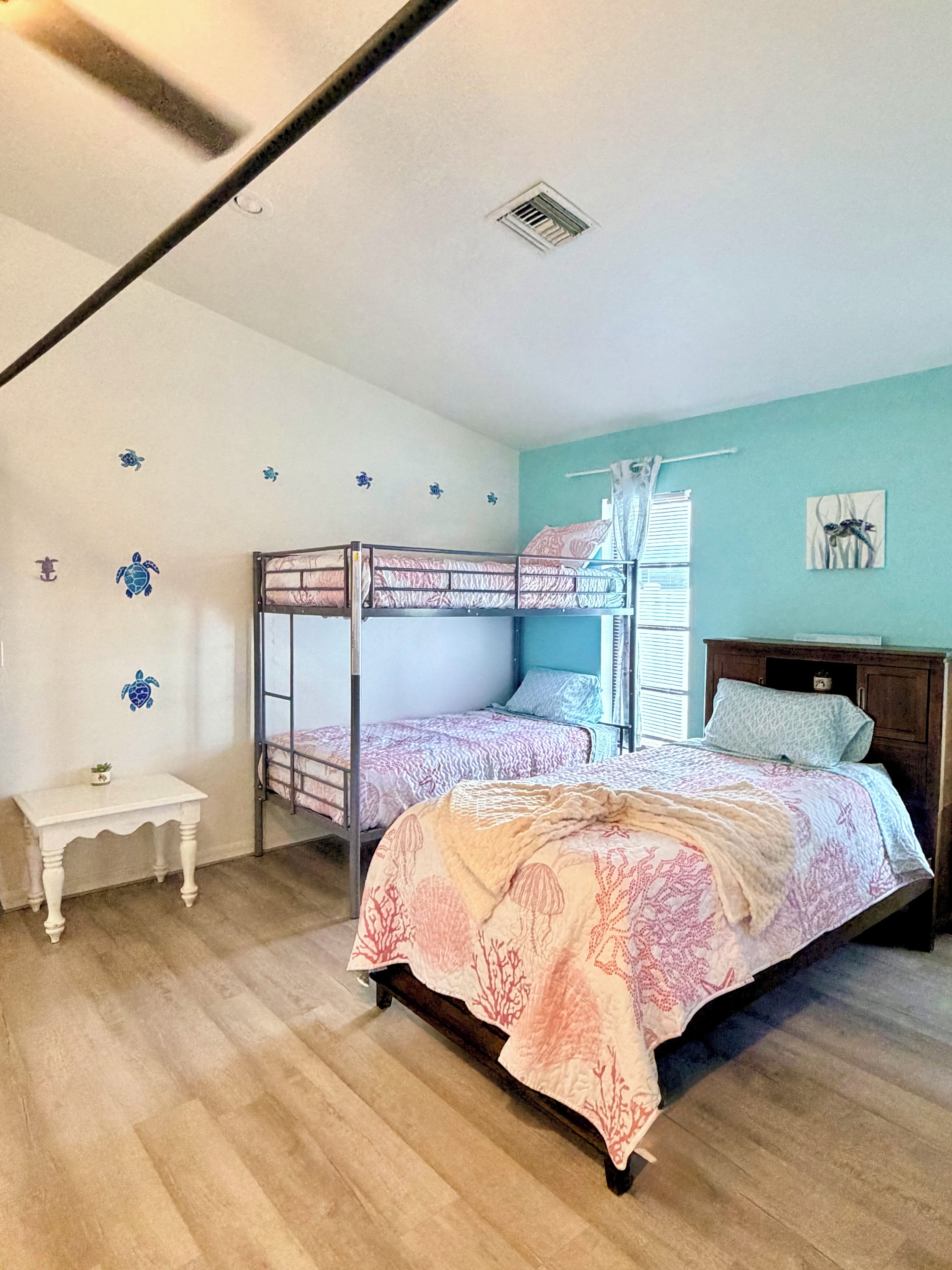 A bedroom with bunk beds, a small table, and decorative wall stickers.