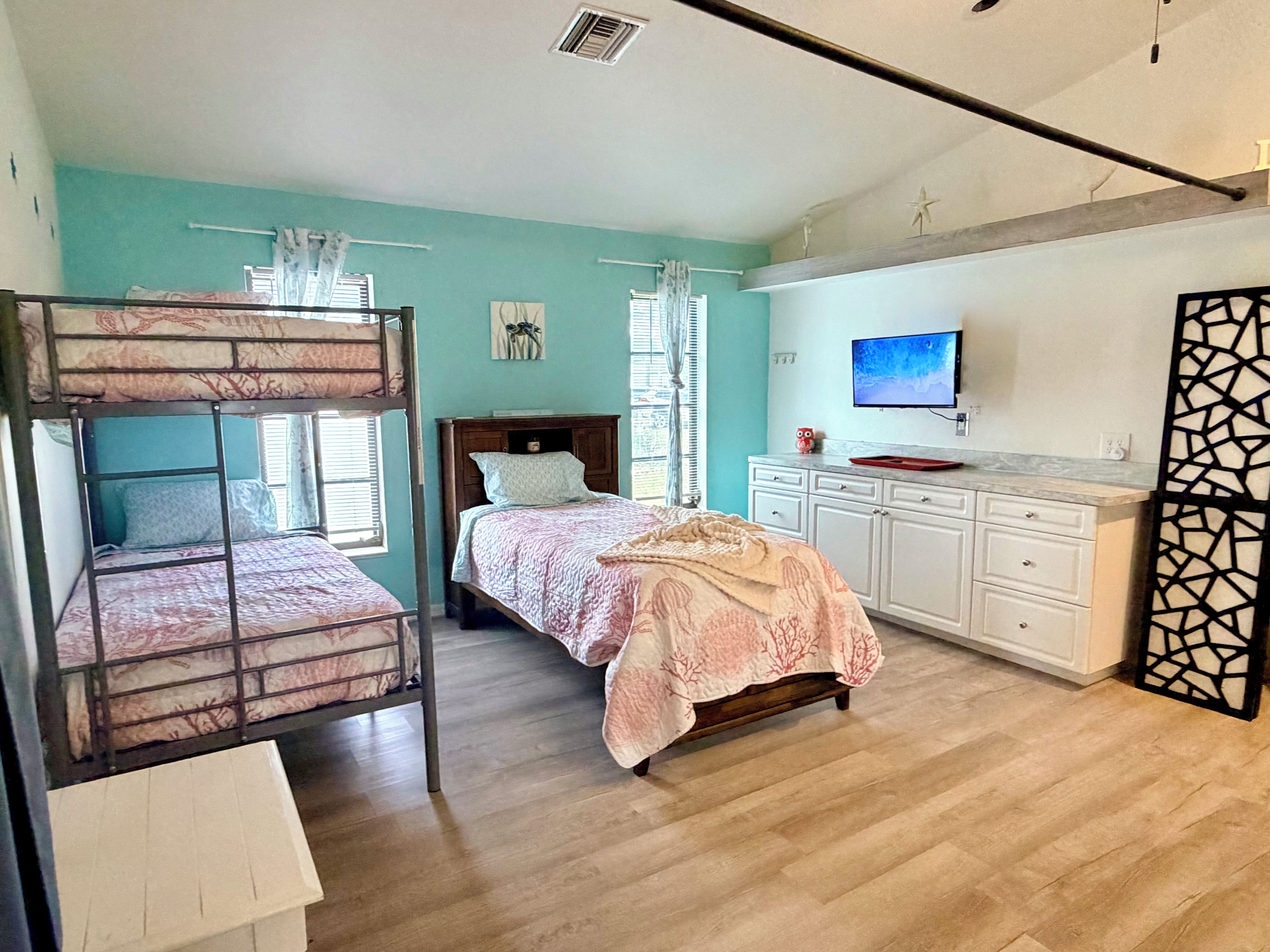 Un dormitorio con literas, una cama individual, un televisor, un escritorio y un armario.