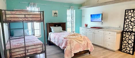 Un dormitorio con literas, una cama individual, un televisor, un escritorio y un armario.