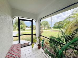 Ein Zimmer mit Blick auf eine grüne Landschaft, eine Bank und Topfpflanzen.
