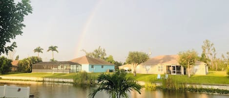 Un barrio residencial con casas, un estanque y un arcoíris.