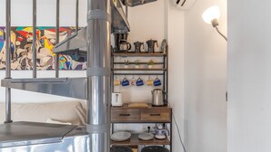 Une cuisine équipée d’une cuisinière en acier inoxydable, d’étagères en bois et d’un luminaire suspendu.