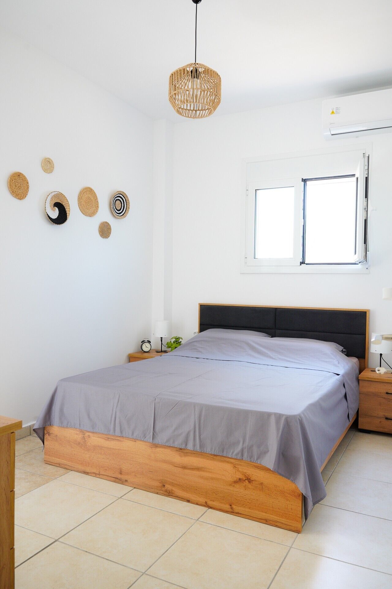 Ein Schlafzimmer mit einem Bett, einer Pendelleuchte, einem Fenster und Wanddekorationen.