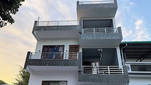 A multi-story residential building with balconies, a stone facade, and a clear sky. - Horizon & Hearth - Scenic Mountain View Villa (Dehradun)