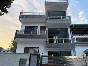 A multi-story residential building with balconies, a stone facade, and a clear sky. - Horizon & Hearth - Scenic Mountain View Villa (Dehradun)