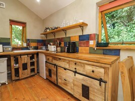 Una cocina con armarios de madera, salpicadero de azulejos y ventana con vistas a la vegetación.