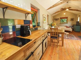Una cocina con cafetera, armarios de madera y una zona de comedor con mesa y sillas.