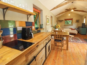 Una cocina con cafetera, armarios de madera y una zona de comedor con mesa y sillas.