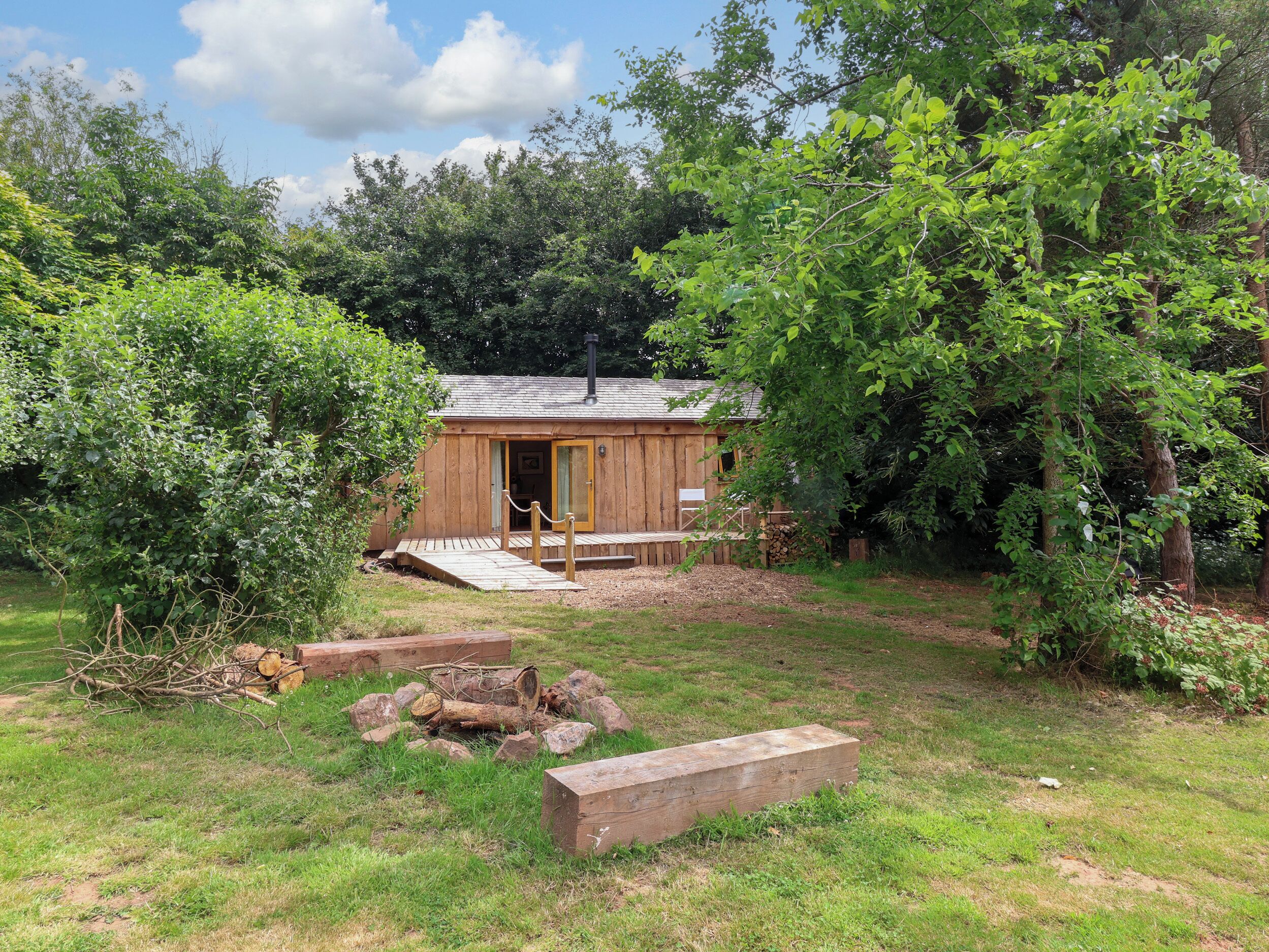 Eine Holzhütte mit Veranda, umgeben von dichtem Grün und Bäumen.