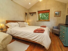 Un dormitorio con cama, lámparas de noche, ventana con vistas, cómoda y una silla.
