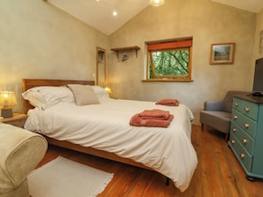 Un dormitorio con cama, lámparas de noche, ventana con vistas, cómoda y una silla.