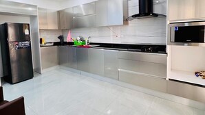 Uma cozinha moderna com eletrodomésticos de aço inoxidável, armários brancos e piso revestido.