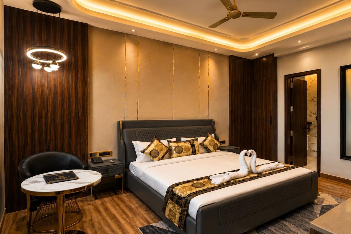 Quarto de hotel moderno com uma cama grande, uma escrivaninha, uma cadeira e um ventilador de teto.