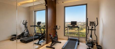 A gym with various exercise equipment, large windows, and a view of the city.