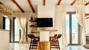 Een moderne eetruimte met een houten tafel, stoelen, een televisie en een groot raam met gordijnen.