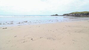 A beach with a sandy shore, calm sea, and distant rocky cliffs. - Teach Feirme (Clonakilty)