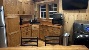 A wooden kitchen with cabinets, a microwave, a toaster, and a washing machine.