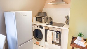 Eine kleine Küchenzeile mit Kühlschrank, Mikrowelle, Backofen und Waschmaschine.