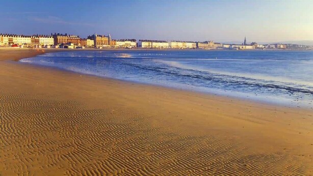 Ein Strand mit einer Reihe von Gebäuden entlang der Küste.