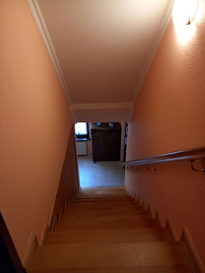 A staircase with a handrail, leading to a room with a radiator and a dark-colored cabinet. - Aemy Vacation Rentals: Central Location (Sellin)