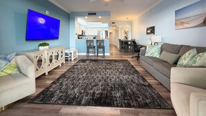 A living room with a TV, sofa, and a patterned rug. - Peaceful Lakefront unit near Disney and Universal (Orlando)