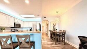 A modern kitchen with white cabinets, a microwave, and a large island with bar stools. - Peaceful Lakefront unit near Disney and Universal (Orlando)