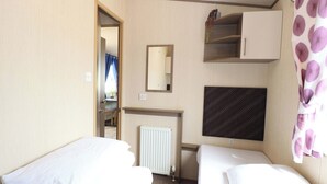 Ett hotellrum med två sängar, ett element, en spegel, en vägg med mönster och en dörr som leder till ett badrum.