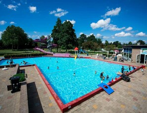 A swimming pool with a red border, a water slide, and a playground area. - Chalet With Stunning Lake Vistas (Heinkenszand)