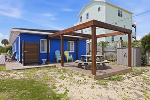 Uma casa azul com um deck de madeira, uma mesa e cadeiras.