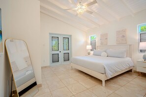 Ein Schlafzimmer mit einem Bett, Nachttischen, einem Spiegel und einem Deckenventilator.